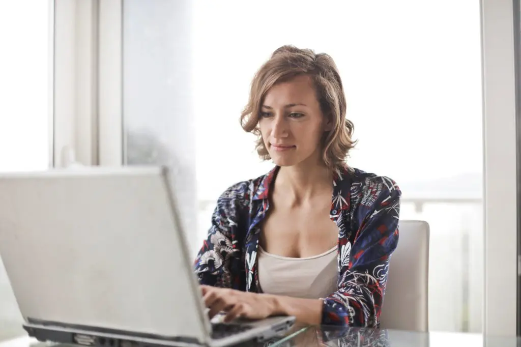 woman in blue floral top sitting while using laptop 806835