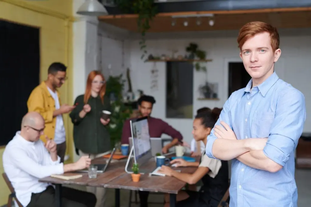 man standing beside people sitting beside table with laptops 3184395