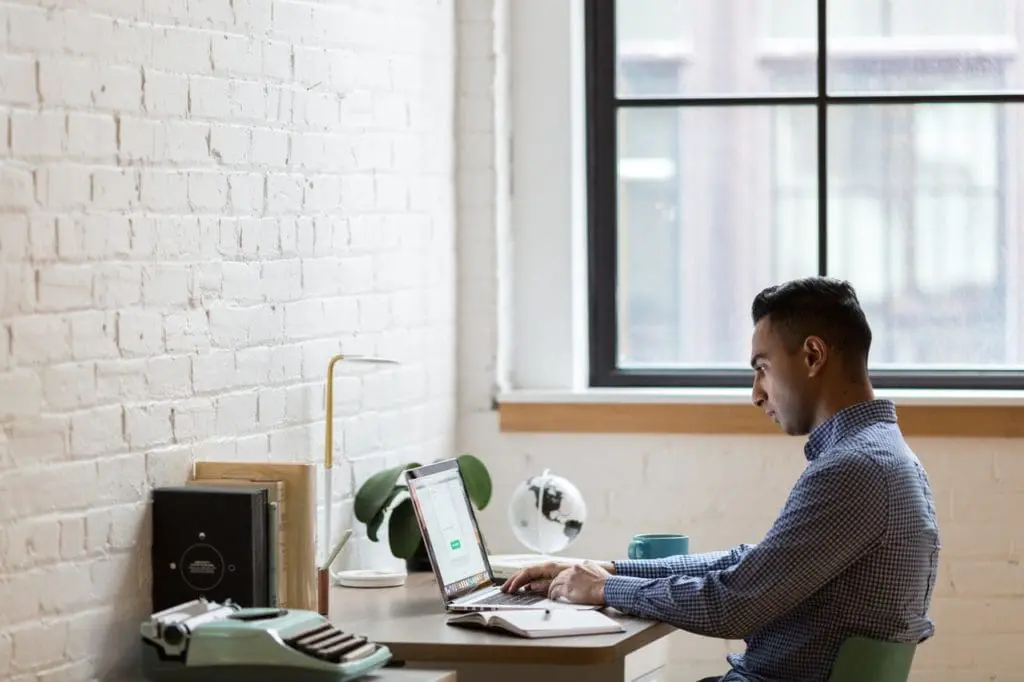 man sitting on green chair while using laptop 374831