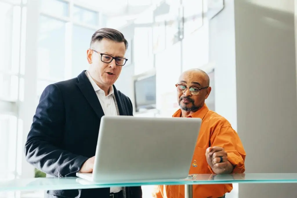 man using silver laptop beside another man 2182973