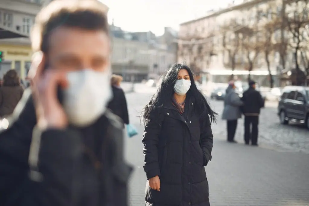 woman in black coat and face standing on street 3983428