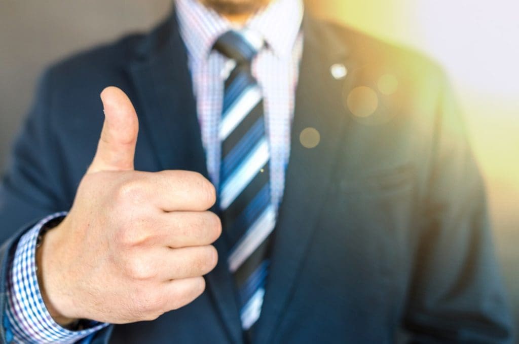 close up photo of man wearing black suit jacket doing thumbs 684385