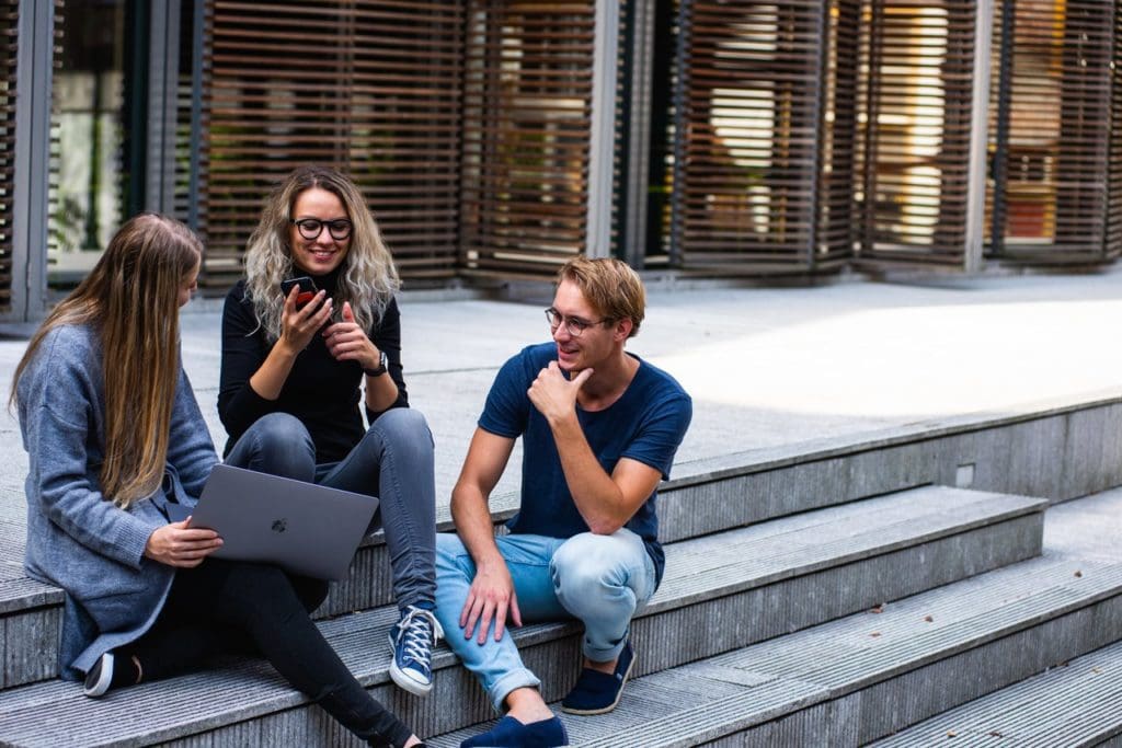 three persons sitting on the stairs talking with each other 1438072